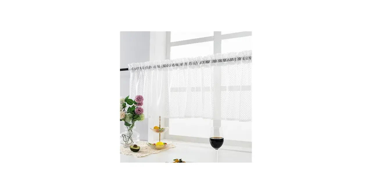Vit gardinkappa och längder med spetskant hänger för ett fönster. Blommor, frukt och ett glas vin på fönsterbrädan.
