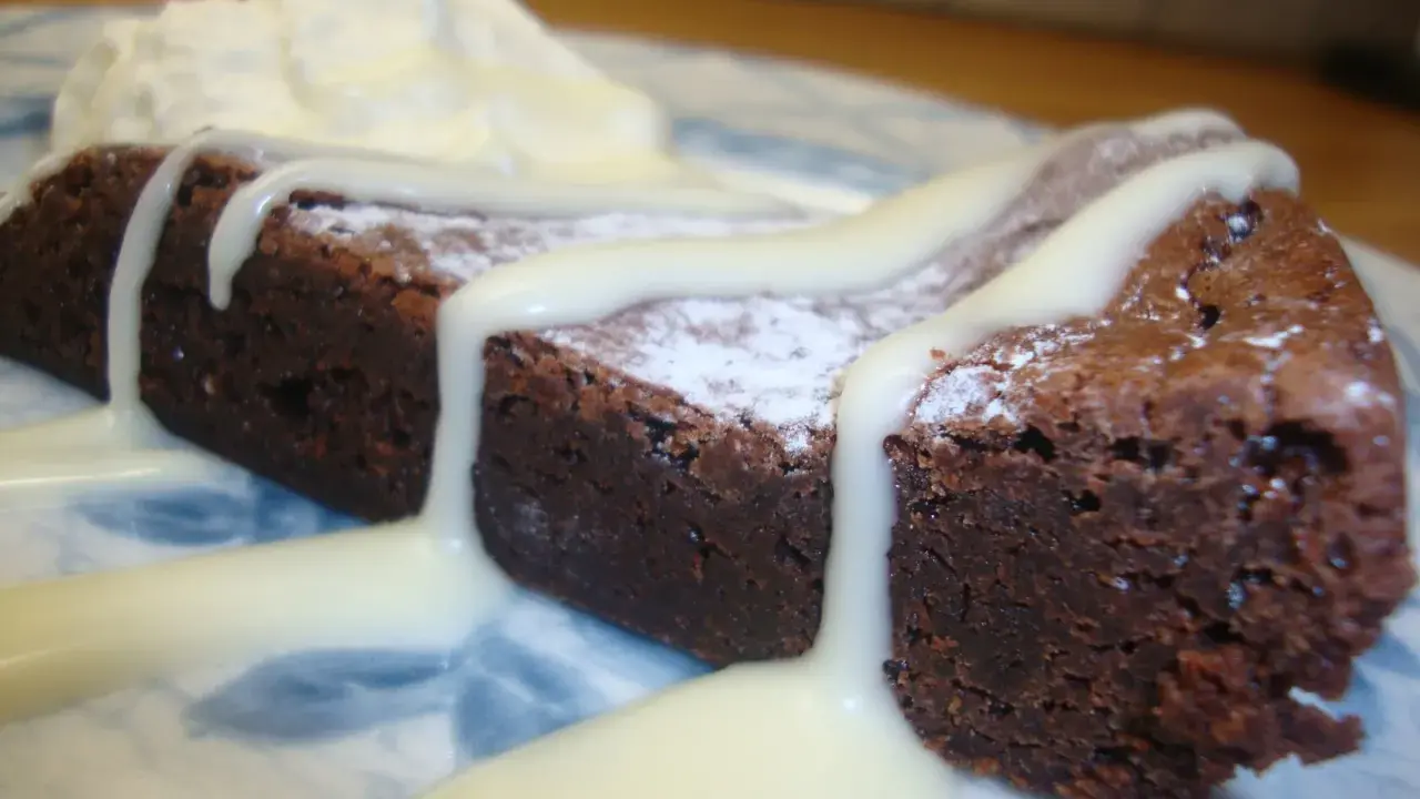 En bit chokladkaka med vispad grädde och vit chokladsås. En härlig vit kladdkaka som smälter i munnen.