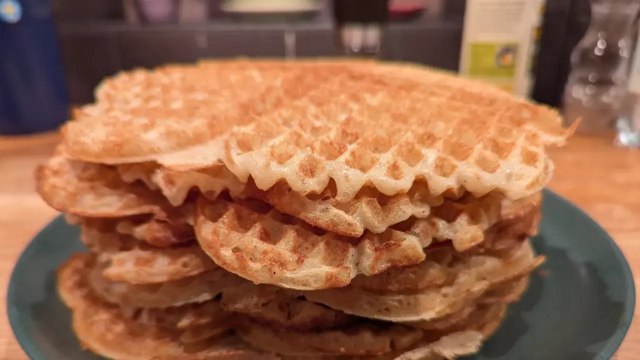 En hög med gyllene, glutenfria våfflor på en grön tallrik. Perfekt för en frukost eller fika!