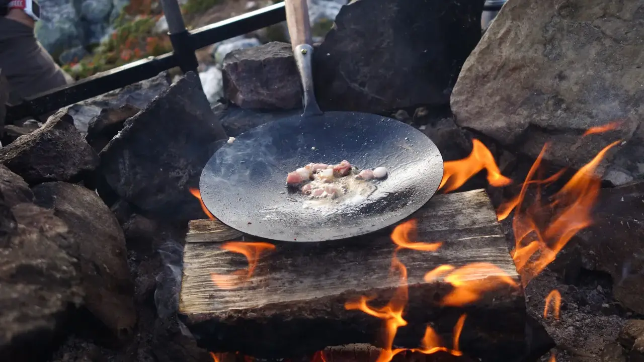 Stekt fläsk på en stekpanna över öppen eld, en del av ett kolbulle recept.