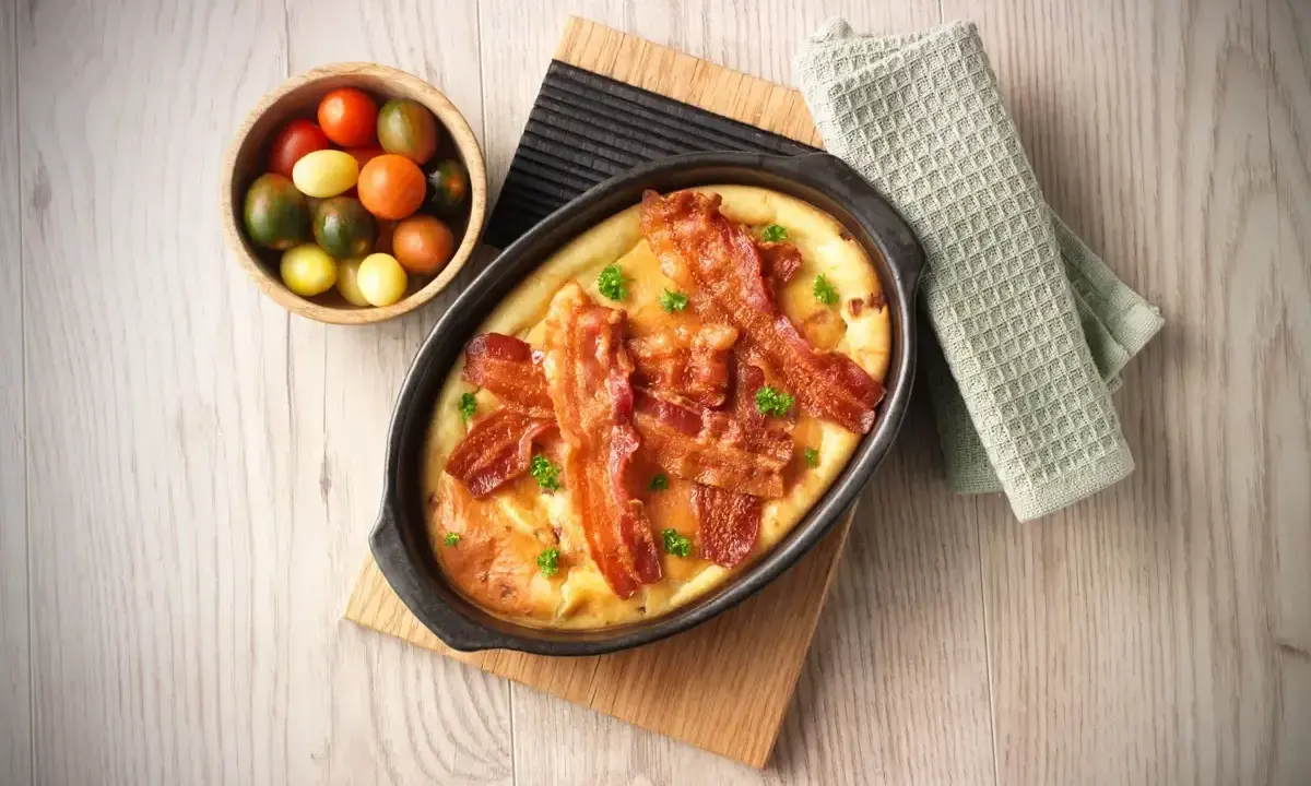 En härlig ugnspannkaka med knaprigt bacon, serverad med en skål körsbärstomater. Perfekt för en mysig frukost eller brunch.