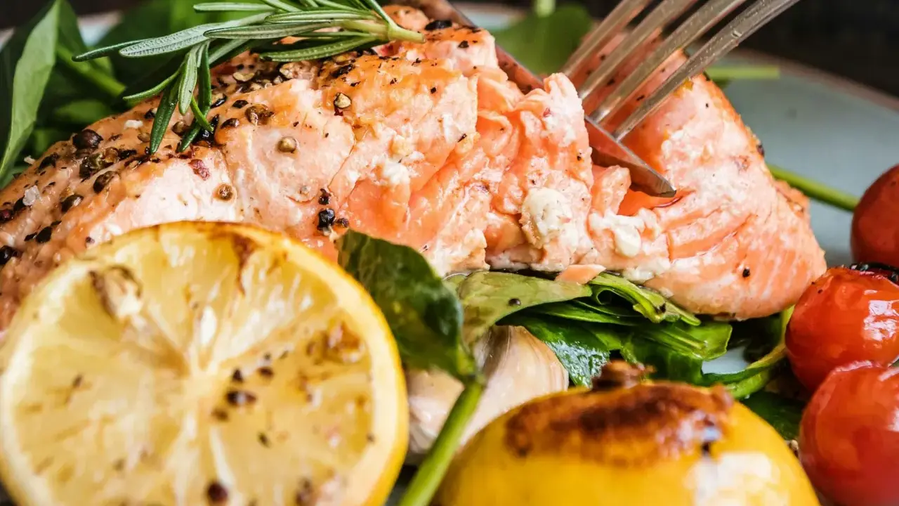 Saftig lax med citron och rosmarin, perfekt för ett enkelt lax recept. Serveras med körsbärstomater och gröna blad.