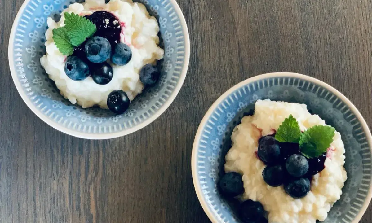 Två skålar med krämig risgrynsgröt, toppad med blåbär och mynta. Ett enkelt och gott risifrutti recept.