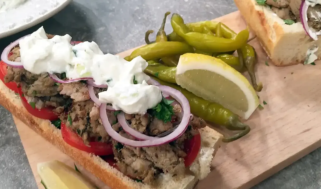 En saftig gyros i baguette med tomater, rödlök och tzatziki. Serveras med pepparfrukter och citronklyfta. Ett perfekt gyros recept!