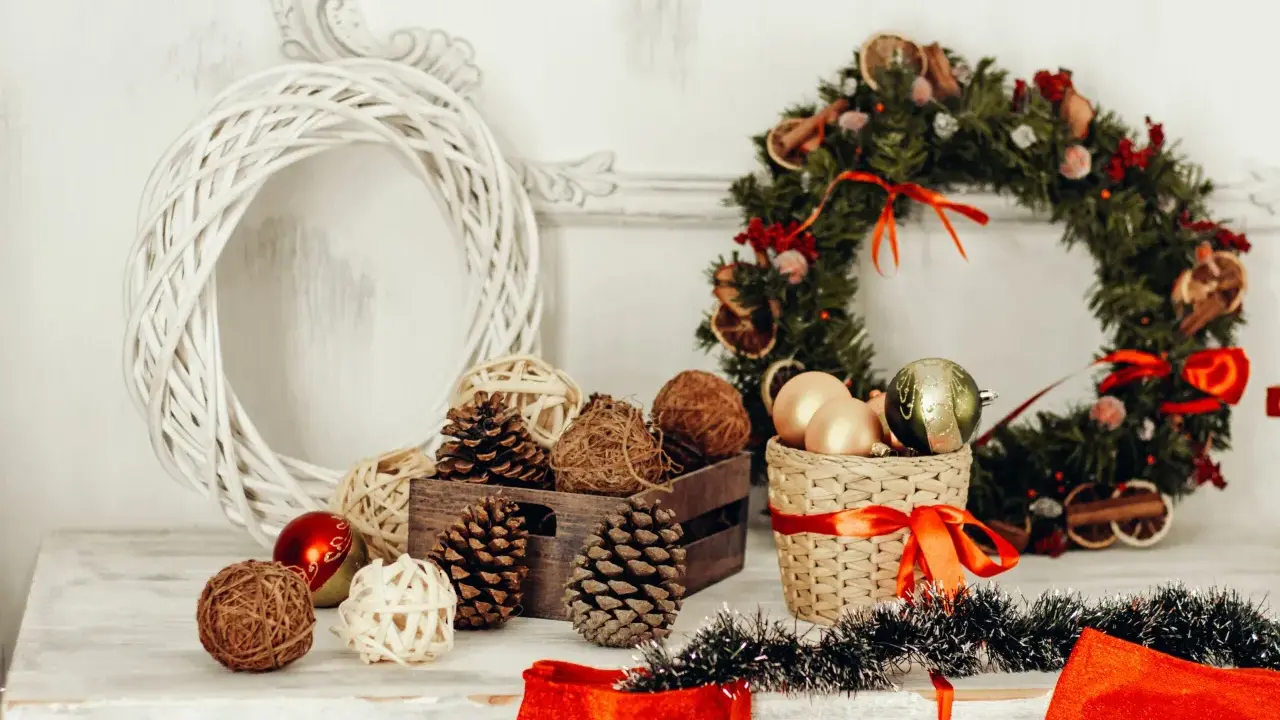 Jul inredning inspiration: en vit flätad krans, julgranskulor, kottar och en grön julkrans med torkad frukt.