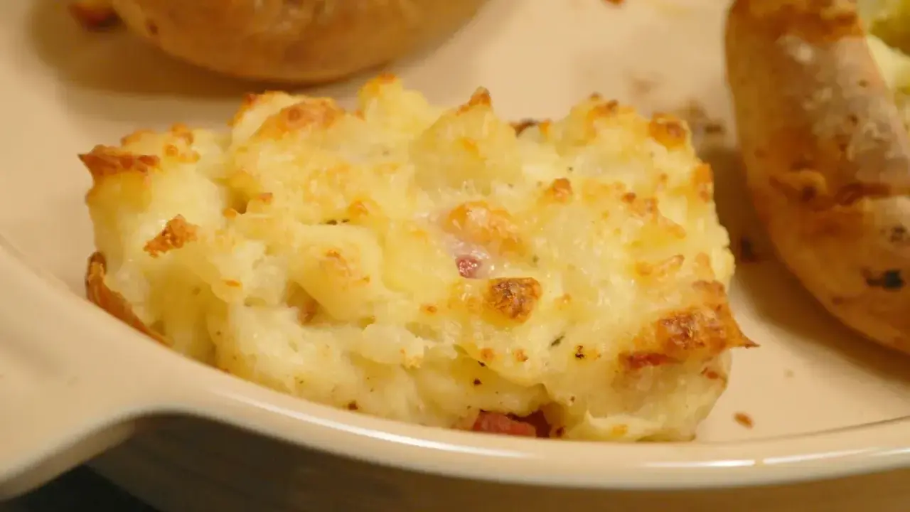 En närbild på en krämig, gratinerad bakad potatis fylld med ost och bacon. En riktig favorit!