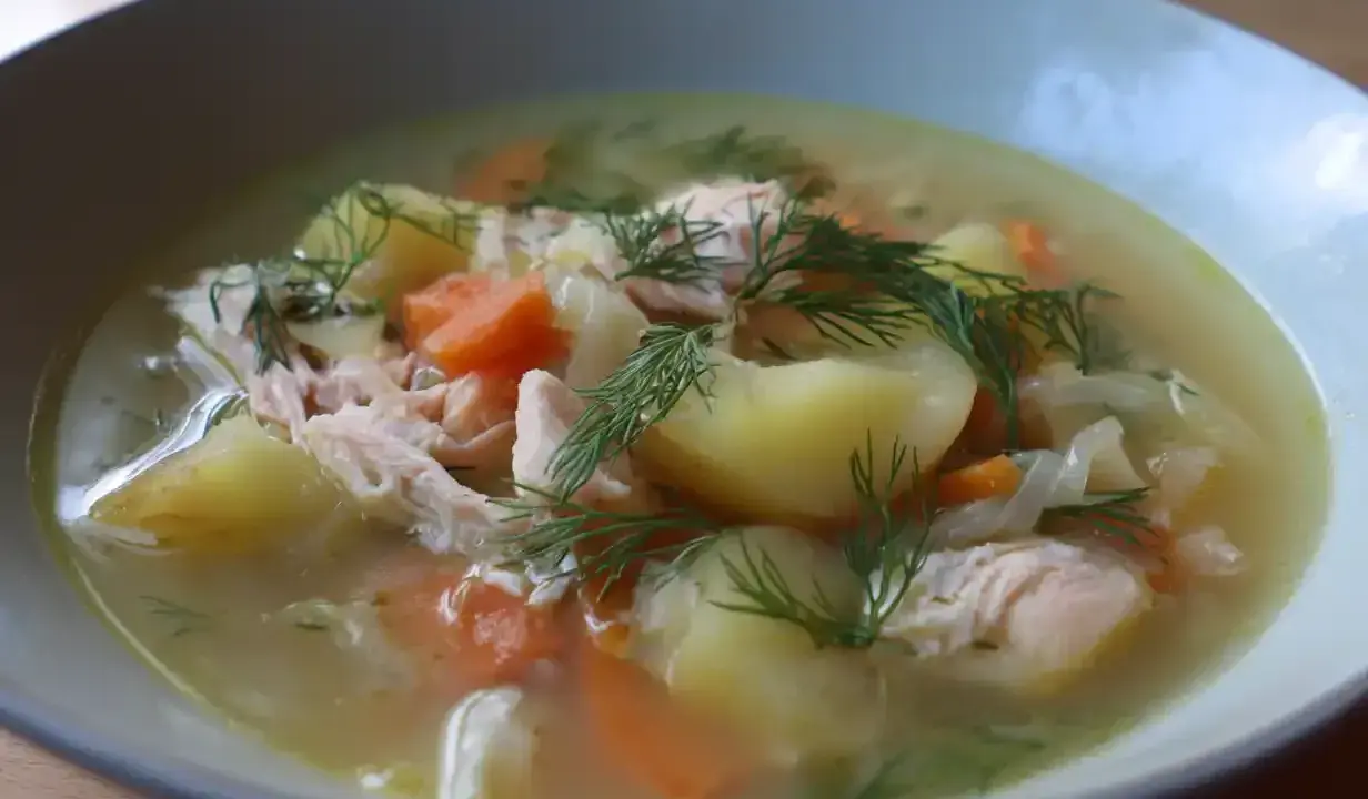 En närbild av en skål med värmande fisksoppa, full av potatis, morötter och dill. Ett perfekt fisksoppa recept för en kall dag.