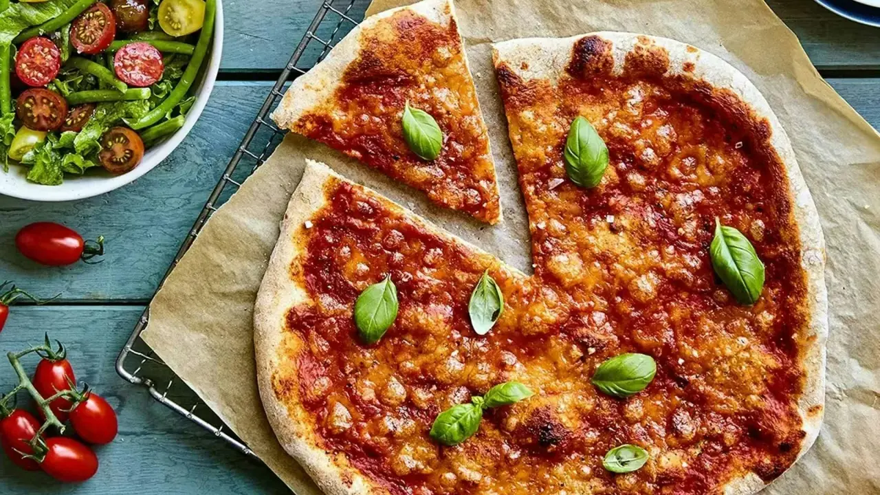 En härlig hemmagjord pizza med tomatsås och ost, toppad med färsk basilika. Bredvid en fräsch sallad med gröna bönor och tomater.