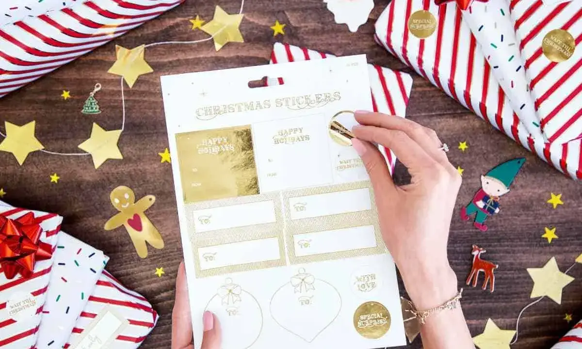 Julklappar inslagna med stjärnor och tomtar. En hand väljer julklappsdekaler, perfekta för julrim barn.
