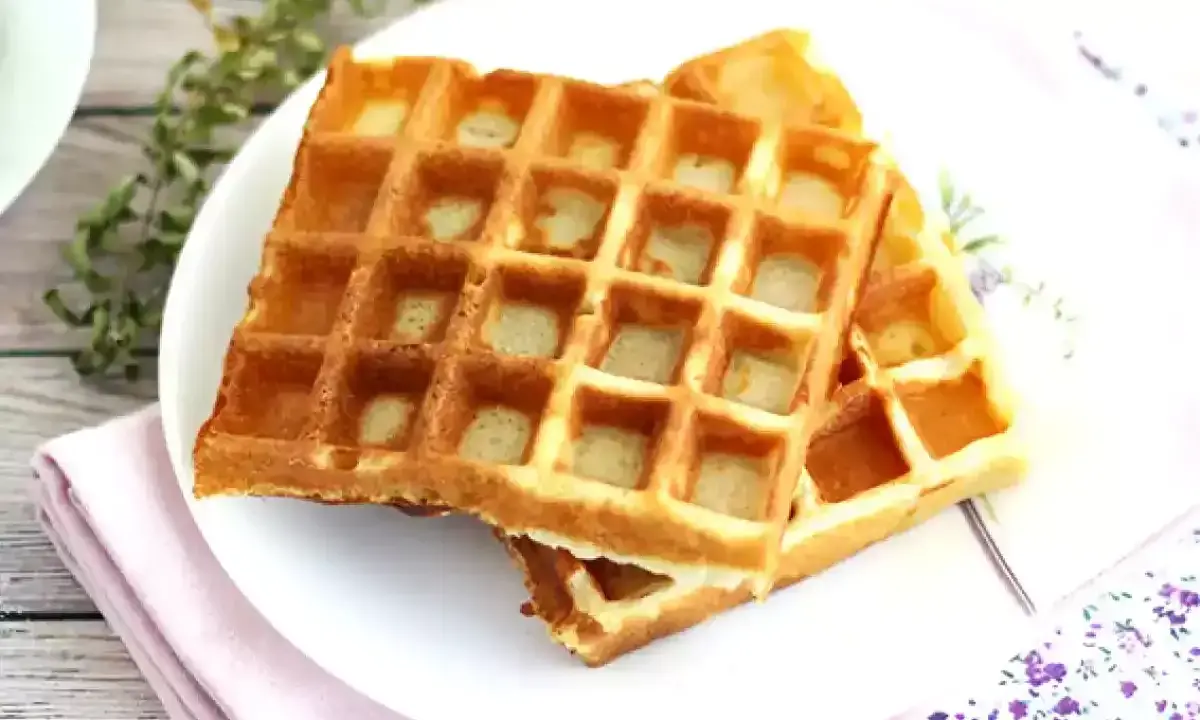 Två gyllene frasvåfflor på en tallrik, redo att avnjutas. Ett perfekt recept för frukost eller fika.