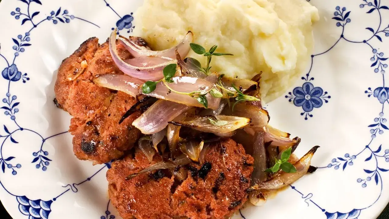 En saftig pannbiff i ugn, toppad med karamelliserad lök och en klick krämigt potatismos. En klassisk svensk rätt som värmer själen.