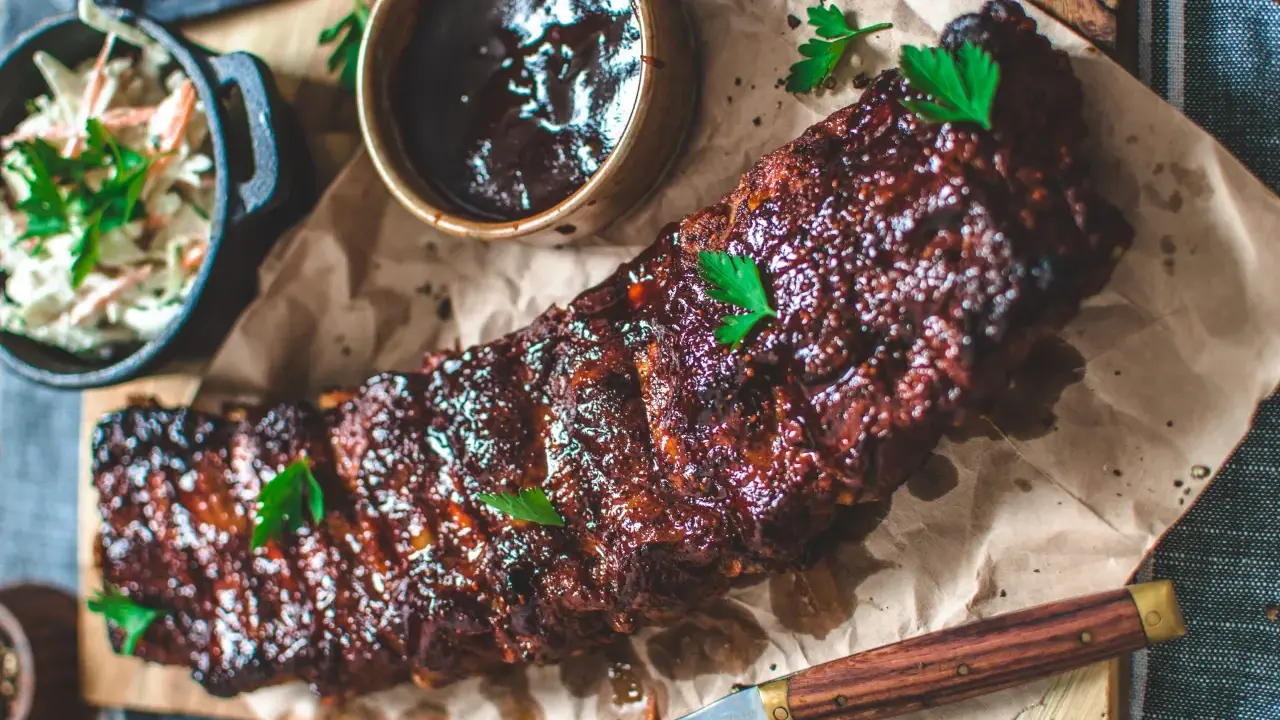 Saftiga spareribs i ugn, glaserade och serverade med en skål coleslaw och BBQ-sås. Perfekt för en härlig middag.