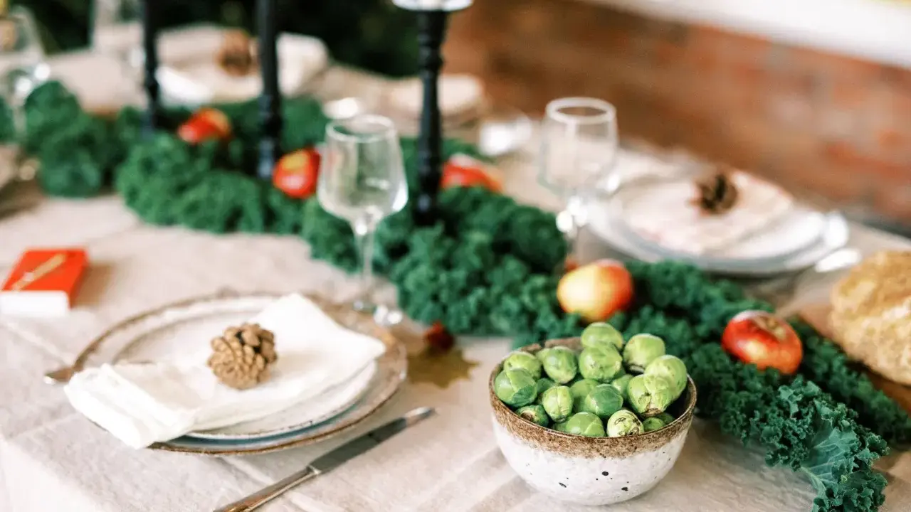 Vacker juldukning inspiration med grönt kale, äpplen och rosenkål. En rustik dukning som bjuder in till fest.