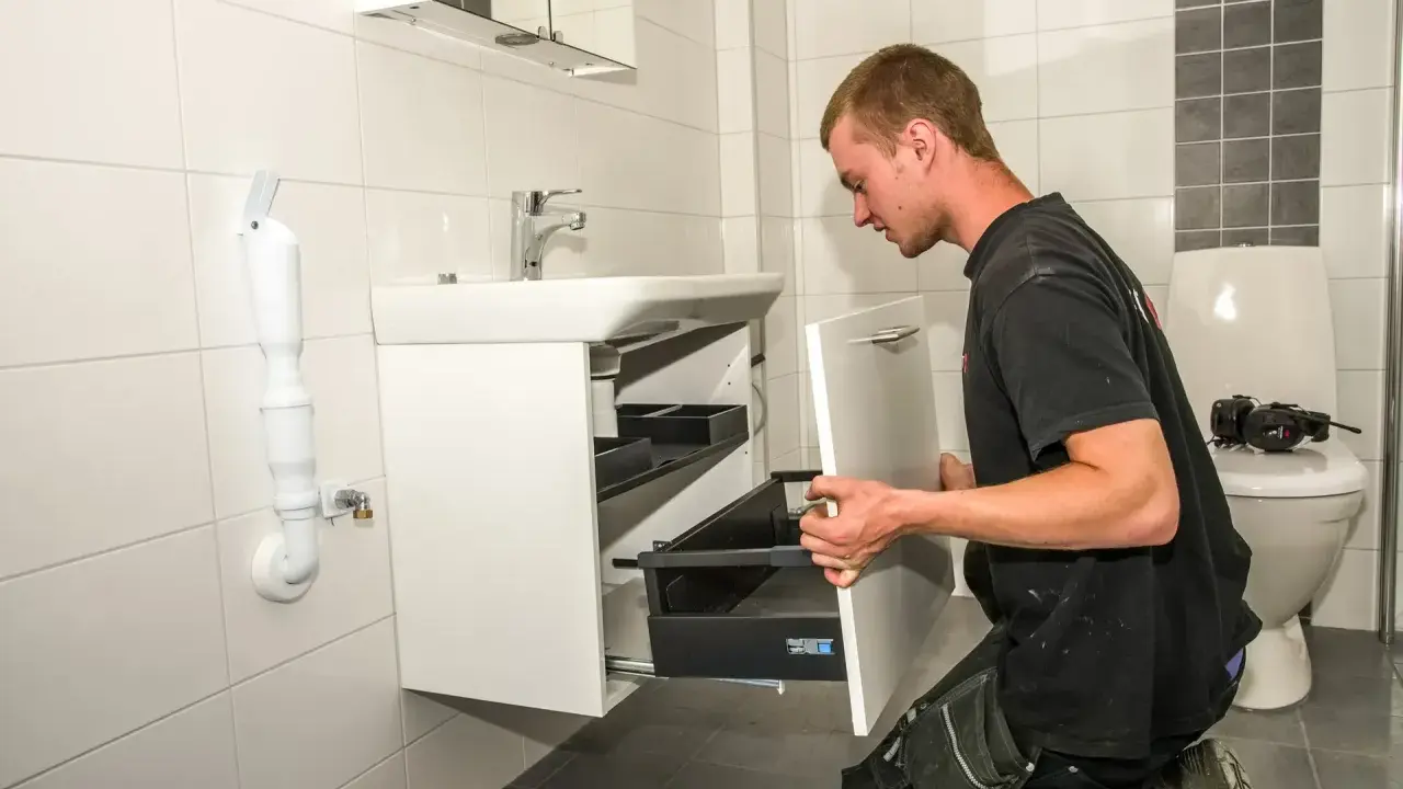 Hantverkare installerar ett nytt badrumsskåp som en del av en totalrenovering badrum.