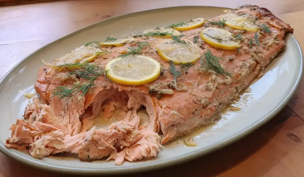 Helstekt lax i ugn, toppad med citronskivor och dill. Perfekt för en middag.