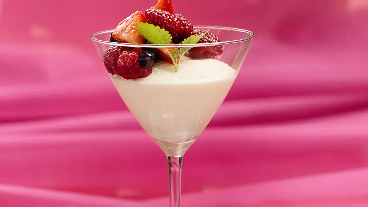 En elegant vit chokladmousse i ett martiniglas, toppad med färska bär och en myntakvist. En dröm för alla som älskar vit chokladmousse.