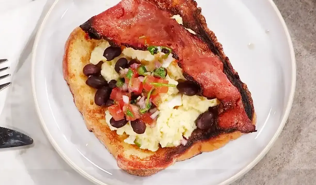 En tallrik med fattiga riddare toppad med äggröra, svarta bönor och salsa.