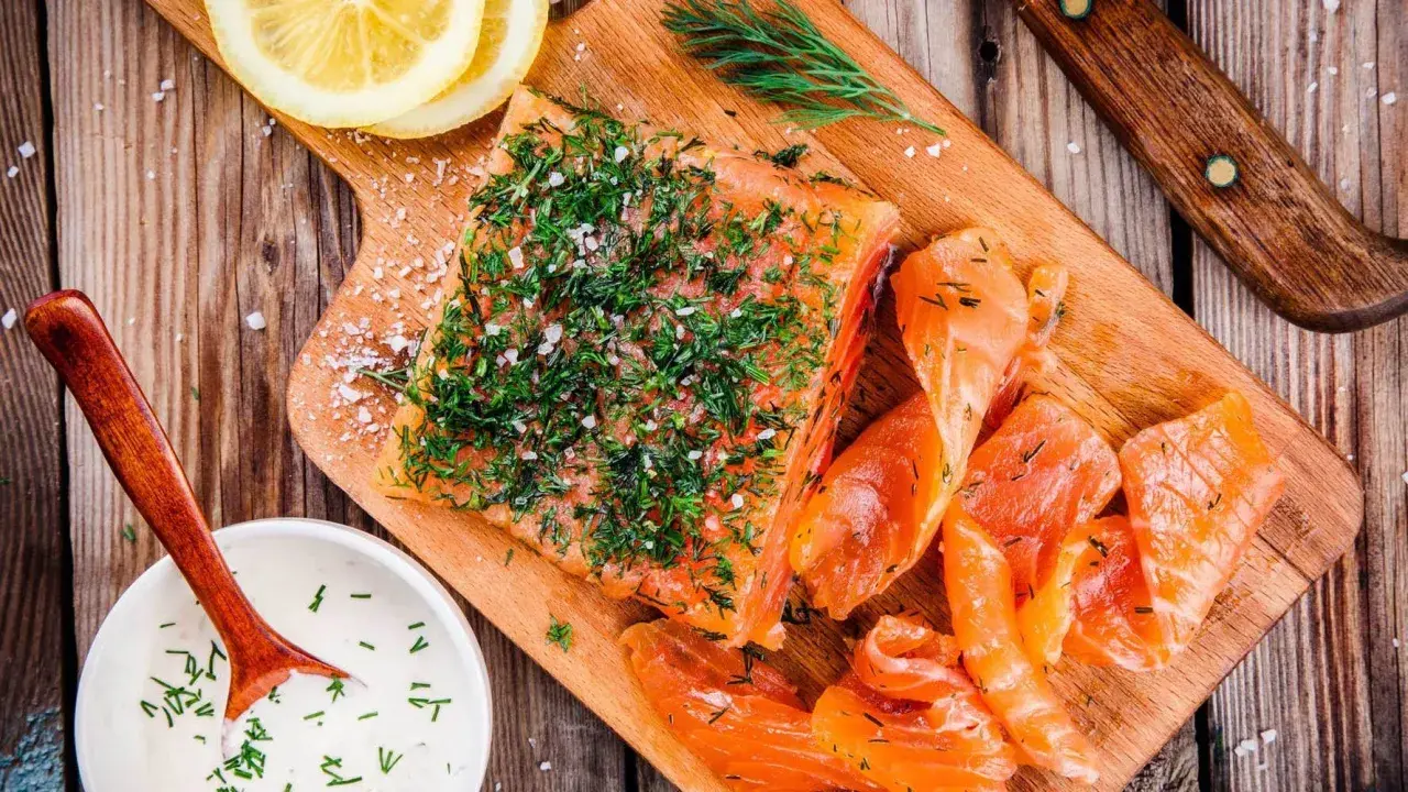 Njut av en bit gravad lax, toppad med dill och salt, serverad med citronskivor och en krämig sås.