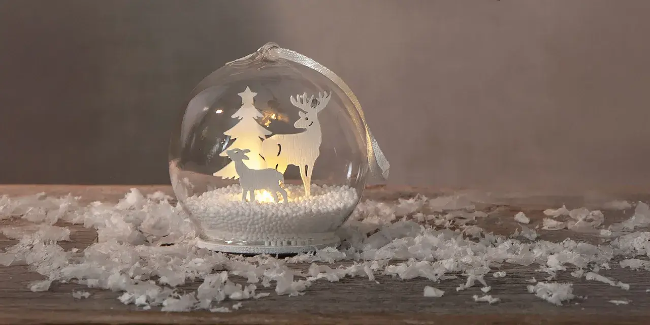 Jul inspiration: en glaskula med renar och gran, omgiven av snö.