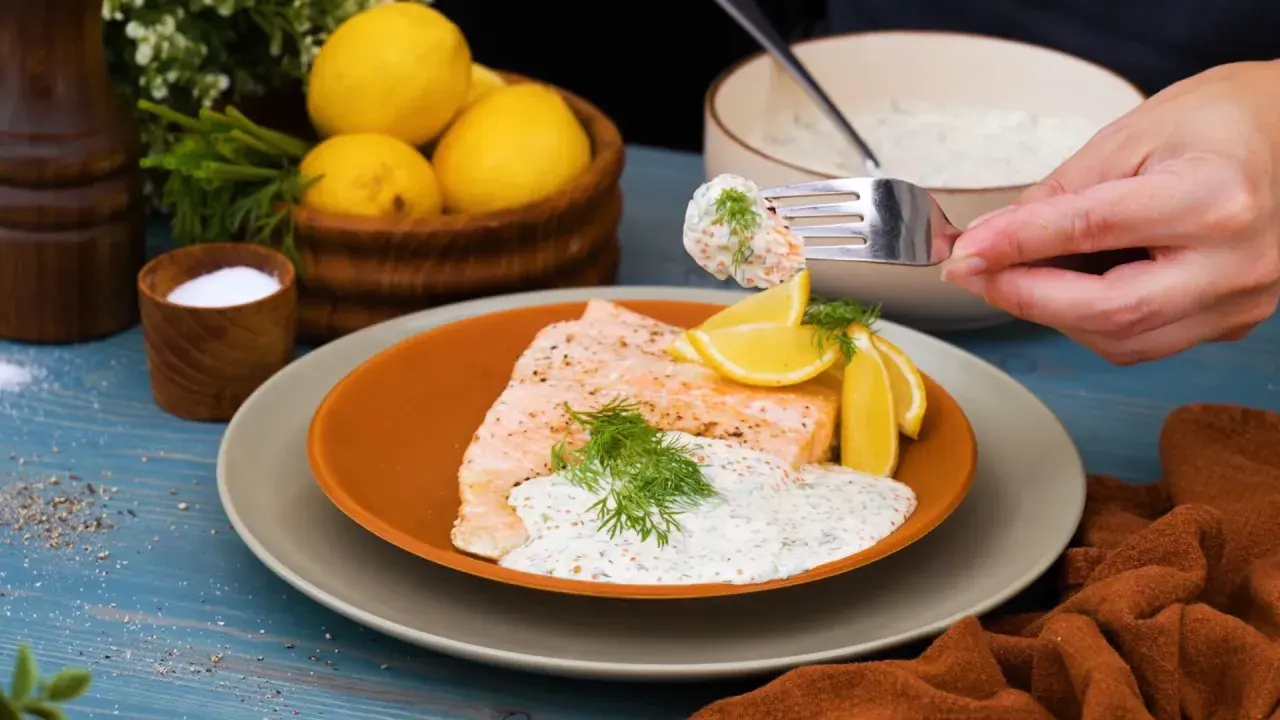 En gaffel med romsås till lax, serverad med citronklyftor och dill. En läcker och fräsch rätt.