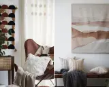 Två vackra tyger på väggen. Ett med geometriskt mönster i jordfärger, det andra med abstrakt akvarellmålning i brunt.