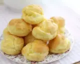 En hög med gyllene petit choux på en vacker tallrik, redo att fyllas med grädde eller glass.
