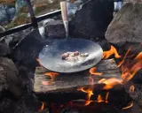Stekt fläsk på en stekpanna över öppen eld, en del av ett kolbulle recept.