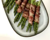 Grön sparris insvept i knaprigt bacon, serverad på en ljusblå tallrik. En läcker och enkel rätt som passar till det mesta.