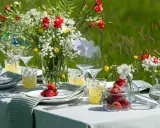 Vackert dukat bord med blommor och jordgubbar för att duka till midsommar.