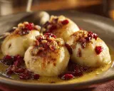 Kroppkakor recept: fyra gyllene kroppkakor med lingon och knaprigt fläsk i en skål.