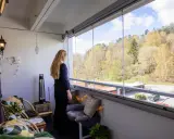 Kvinna njuter av utsikten från inglasad balkong. Mysiga sittplatser och lampor ger fina balkong tips för en ombonad känsla.