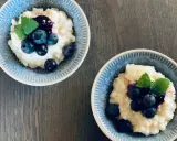 Två skålar med krämig risgrynsgröt, toppad med blåbär och mynta. Ett enkelt och gott risifrutti recept.