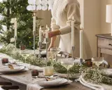Vacker dukning med ljus och blommor för att duka till nyår. En person fyller på glas.
