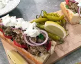 En saftig gyros i baguette med tomater, rödlök och tzatziki. Serveras med pepparfrukter och citronklyfta. Ett perfekt gyros recept!