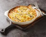 En krämig Janssons frestelse med potatis, ansjovis och ströbröd i en ugnsform, redo att serveras med två silvergafflar.