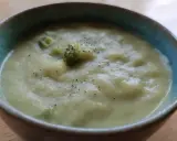 En krämig potatis och broccolisoppa, toppad med lite svartpeppar, serveras i en blå kantad skål.