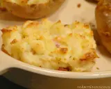 En närbild på en krämig, gratinerad bakad potatis fylld med ost och bacon. En riktig favorit!