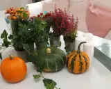 Förberedelser för att dekorera pumpa med höstblommor, ljus och murgröna.