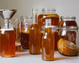 Flera flaskor och burkar med hemgjord kombucha, redo för andra jäsningen. Ett perfekt kombucha recept för hemmabruk.