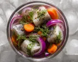 En skål med inlagd sill, morötter, rödlök och dill, omgiven av is. En klassisk svensk delikatess.