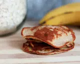 En hög med gyllenbruna, nyttiga pannkakor, gjorda på havregryn och banan, ligger på en träskärbräda.