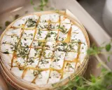 En härlig brie i ugn, gyllene och bubblande, toppad med örter. Perfekt för att doppa bröd i.