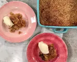 En härlig glutenfri rabarberpaj med en krispig topping, serverad med vaniljglass på rosa och röda tallrikar.