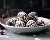En skål med chokladbollar, perfekta för ett enkelt chokladbollar recept. Garnerade med kokosflingor och med några körsbär bredvid.