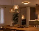 Tre vackra taklampor i glas hänger över ett träbord. En mysig kväll i hemmet.