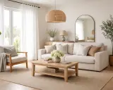 Ljust och luftigt vardagsrum med bekväm soffa, fåtölj och ett soffbord i trä. Den stilrena möbleringen skapar en inbjudande atmosfär.