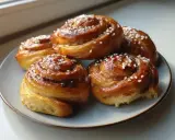 Fem gyllene kanelbullar med pärlsocker på en ljusblå tallrik. Perfekt för ett kanelbullar recept.