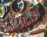 Saftiga spareribs i ugn, glaserade och serverade med en skål coleslaw och BBQ-sås. Perfekt för en härlig middag.