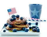 Amerikansk bananpannkaka recept med blåbär och en liten flagga. Perfekt för en festlig frukost!
