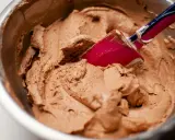 Chokladkräm i en skål, redo att bli glass. En rosa slickepott blandar i den lena smeten, kanske med lite xantangummi för perfekt konsistens.